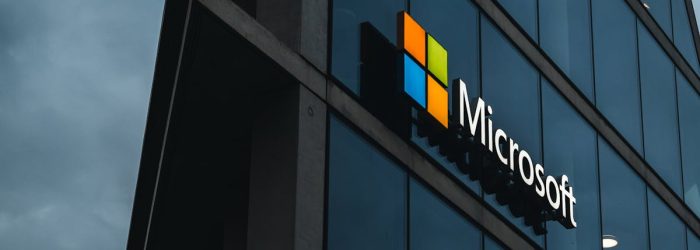 A modern Microsoft office skyscraper with glass facade against a cloudy evening sky.