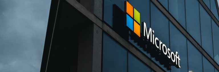 A modern Microsoft office skyscraper with glass facade against a cloudy evening sky.